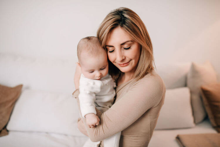 Mama mit Baby im Arm haltend